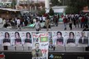 People walk past election campaign posters of different parties, in Irbil, Iraq, 350 kilometers (217 miles) north of Baghdad, Friday, Sept. 20, 2013, a day ahead of the self-ruled northern Kurdish region's fourth election for local parliament since 1992. (AP Photo/ Khalid Mohammed)