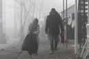 A couple of refugees walks in the fog at the transit center for refugees near northern Macedonian village of Tabanovce, Tuesday, Feb. 2, 2016. As Europe struggles to cope with the influx of more than 1 million migrants in 2015 alone, countries are increasingly coming up with new procedures to cope with them. (AP Photo/Boris Grdanoski)