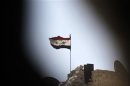 A Syrian national flag flutters over a building controlled by forces loyal to President Bashar Al-Assad in Ashrafieh, Aleppo