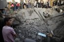 Palestinians gather around destroyed house as members of civil defence search for victims under rubble after an Israeli air strike in Gaza City