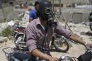 A man drives his motorcycle as he wears a gas masks after what activists said was a chlorine gas attack on Kansafra village at Idlib countryside