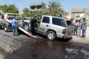 A damaged car is removed from the site of a car bomb attack against the convoy of Riyadh al-Adhadh, the chief of the provincial council, on September 15, 2013 in Baghdad
