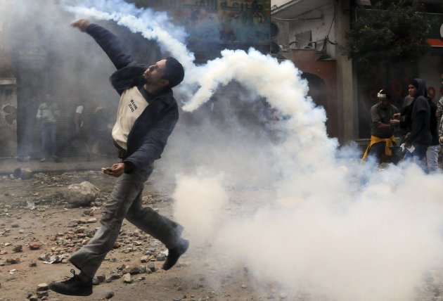 A protester throws a tear gas canister, which had earlier been thrown by riot police, near Tahrir Square in Cairo