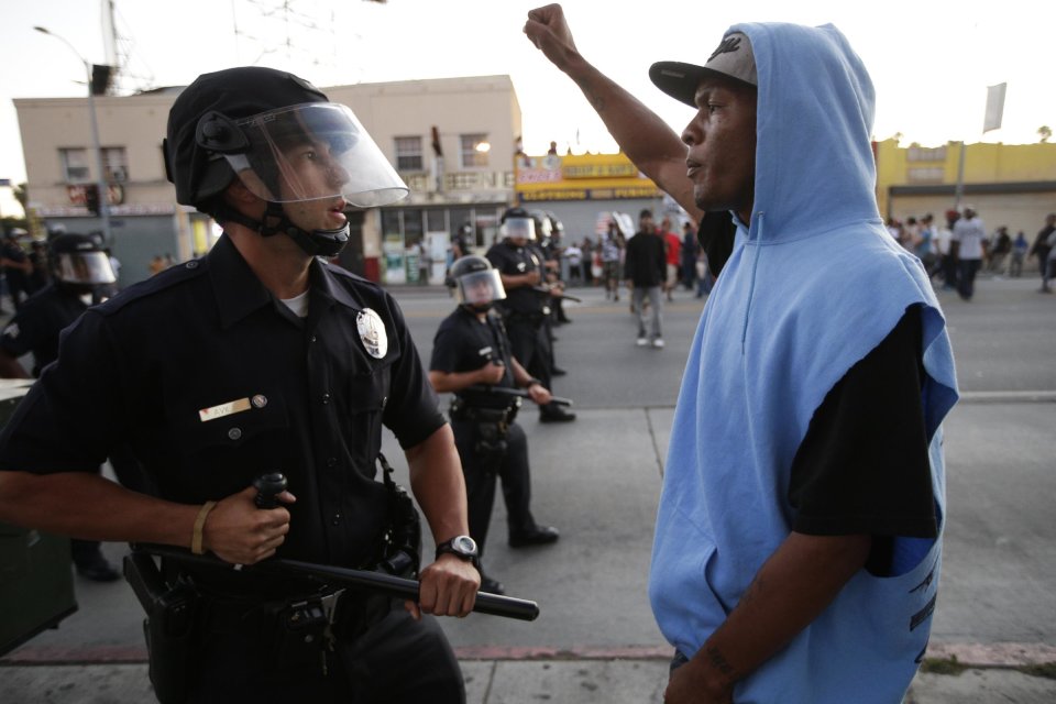 A protester confronts a Los Angles police officer during a demonstration in reaction to the acquittal of neighborhood watch volunteer George Zimmerman on Monday, July 15, 2013, in Los Angeles. Anger over the acquittal of a U.S. neighborhood watch volunteer who shot dead an unarmed black teenager continued Monday, with civil rights leaders saying mostly peaceful protests will continue this weekend with vigils in dozens of cities. (AP Photo/Jae C. Hong)