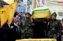Hezbollah members carry the coffin of top Hezbollah commander Mustafa Badreddine, who was killed in an attack in Syria, as his brother mourns his death during his funeral in Beirut's southern suburbs