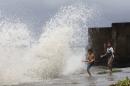 Boys play next to strong waves in a coastal village as strong winds from Typhoon Haiyan battered Bayog town in Los Banos, Laguna, south of Manila