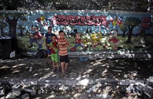 Palestinian boys stand next to wall with murals and &hellip;