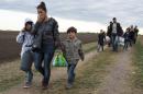A migrant family from Syria walks along rail tracks as they arrive to a collection point in the village of Roszke, Hungary