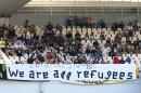 Syrian refugees, invited by AEK Athens' fans, sit behind a banner while watching the soccer match between AEK Athens and PAS Giannena for the Greek Soccer League at the Olympic stadium of Athens, Sunday, Sept. 13, 2015. At least 28 people seeking a better life in Europe drowned Sunday as they attempted a wind-swept sea crossing from Turkey to Greece, while a record number of asylum seekers reached Hungary's border with Serbia just two days before the government vows to make its southern frontier more difficult to cross. (Nikos Vichos/InTime Sports via AP) GREECE OUT