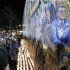 People gather in front of a mural containing a likeness of former Penn State football coach Joe Paterno, right, at a candlelight memorial on the first anniversary of his death, Tuesday, Jan. 22, 2013, in State College, Pa. (AP Photo/Gene J. Puskar)