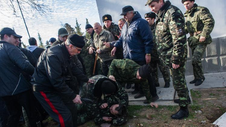 Unarmed members of Pro-Russian self-defense forces, left, force themselves through a chain of Ukrainian military men at the Ukrainian Navy headquarters in Sevastopol, Crimea, Wednesday, March 19, 2014. An Associated Press photographer said several hundred militiamen took down the gate and made their way onto the base. They then raised the Russian flag on the square by the headquarters. The unarmed militia waited for an hour in the square before the move to storm the headquarters. Following the arrival of the commander of the Russian Black Sea fleet, the Crimeans took over the building. (AP Photo/Andrew Lubimov)
