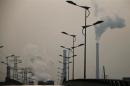 Smoke rises from chimneys of a steel plant next to a viaduct on a hazy day in Tangshan