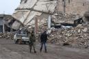 Rebel fighters walk near damaged buildings in al-Rai town, northern Aleppo countryside