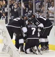 Los Angeles Kings defenseman Rob Scuderi (7) is helped up by teammates after being hit from behind by New Jersey Devils right wing Steve Bernier (18) in the first period, during Game 6 of the NHL hockey Stanley Cup finals, Monday, June 11, 2012, in Los Angeles.  (AP Photo/Mark J. Terrill)