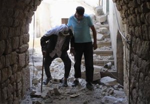 A man helps elderly make way through rubble of house …