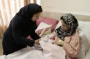 Iranian nurse Zahra Akbarzadeh, left, gives one-day-old baby girl Setayesh to her mother, Tayyebeh Sadat Bidak, to feed her at the Mehr hospital, in Tehran, Sunday, July 29, 2012. In a major reversal of once far-reaching family planning policies, Iran is now slashing its birth-control programs in an attempt to avoid an aging demographic similar to many Western countries that are struggling to keep up with state medical and social security costs. (AP Photo/Vahid Salemi)