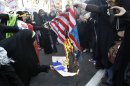 Iranian demonstrators burn a representation of a U.S. flag and a caricature of President Barack Obama, in an annual state-backed rally in front of the former US Embassy in Tehran, Iran, Friday, Nov. 2, 2012. The rally marks the Nov. 4, 1979, storming of the building by militant students who held 52 Americans hostage for 444 days to protest U.S. failure to hand over the toppled shah Mohammad Reza Pahlavi to Iran for trial. Gen. Mohammad Reza Naqdi of the powerful Revolutionary Guard, not shown, addressed the rally saying the U.S. must annul the CIA, pull out its warships from the Persian Gulf and dismantle its military bases from 50 countries around the world if it wants to restore ties with Tehran. (AP Photo/Vahid Salemi)