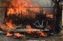 Flames blaze from a property at the site of a wildfire in Tres Cantos, north of Madrid on August 22, 2013