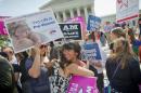 Demonstrators embrace as they react to hearing the Supreme Court's decision on the Hobby Lobby case outside the Supreme Court in Washington, Monday, June 30, 2014. The Supreme Court says corporations can hold religious objections that allow them to opt out of the new health law requirement that they cover contraceptives for women.(AP Photo/Pablo Martinez Monsivais)
