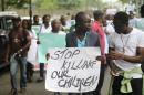 Youths and workers carrying signs protest at a rally marking May Day outside an open field in Lagos