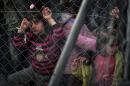 Children, behind a fence, wait to cross the Greek-Macedonian border along with other Syrian and Iraqis refugees near the village of Idomeni on February 27, 2016