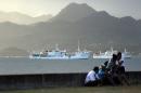 Locals sit on a wall situated on the foreshore of the harbour in the Fiji capital of Suva