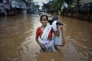An Indian woman wades through the floodwaters in Gauhati, India, Friday, June 27, 2014. Several people were killed due to electrocution and landslides triggered by incessant rains in India's northeastern state of Assam, according to local reports. (AP Photo/Anupam Nath)