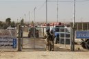 Iraqi army soldiers stand guard at a gate refugee camp in al-Qaim