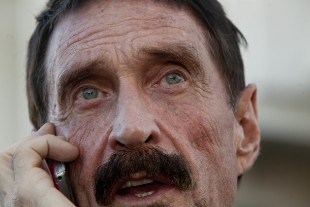 Software company founder John McAfee talks on his mobile phone after a press conference outside the Supreme Court in Guatemala City, Tuesday, Dec. 4, 2012. McAfee, 67, who has been identified as a "person of interest" in the killing of his neighbor in Belize, 52-year-old Gregory Faull, has surfaced in public for the first time in weeks, saying Tuesday that he plans to ask for asylum in Guatemala because he fears persecution in Belize. (AP Photo/Moises Castillo)
