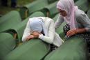 A Bosnian Muslim woman, a survivor of the Srebrenica 1995 massacre, cries by the coffin of a relative, layed out among others at the memorial cemetery in the village of Potocari near the eastern-Bosnian town of Srebrenica, on July 11, 2014