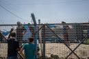 Men speak through a fence surrounding an area where newcomers are interrogted at Dibaga camp for internally displaced civilians in Iraq, on August 7, 2016. (AP Photo/Alice Martins)