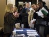 Job seekers adjust their paperwork as they wait in line to attend a job fair in New York