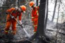 Cpl. Kevin Deng, right, and M.Cpl. Casey Zaharoff, members of the Canadian Forces, put out a hotspot from wildfires near Montreal Lake, Saskatchewan, Thursday, July 9, 2015. Large wildfires raging across Canada have contributed to a smoky haze lingering above the Western U.S., blazes fueled by the familiar hot, and dry conditions that have turned much of the region into a tinderbox. (Jeff McIntosh/The Canadian Press via AP) MANDATORY CREDIT