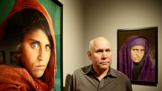 US photographer Steve McCurry poses next to his photos of &quot;Afghan Girl&quot; Sharbat Gula at an exhibition of his work in Hamburg, Germany in June 2013