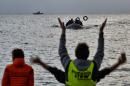 Volunteers gesture to guide refugees and migrants on a dinghy as they approach Mytilene on the northern island of Lesbos after crossing the Aegean sea from Turkey on February 19, 2016