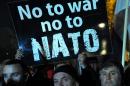 Protesters hold a sign reading "No to war, no to NATO" during a protest in Podgorica on December 12, 2015