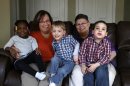 FILE- In a March 5, 2013 photo, April DeBoer, second from left, sits with her adopted daughter Ryanne, 3, left, and Jayne Rowse, fourth from left, and her adopted sons Jacob, 3, middle, and Nolan, 4, right, at their home in Hazel Park, Mich. A judge is refusing to dismiss a lawsuit by the two women challenging Michigan's ban on gay marriage and joint adoptions by same-sex couples. Detroit federal Judge Bernard Friedman says Rowse and DeBoer 