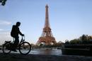 A man rides his bicycle near the river Seine in front of the Eiffel tower in Paris on May 6, 2013