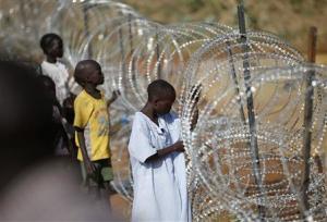Internally displaced boys stand next to barbed wire&nbsp;&hellip;