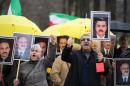 Members of the People's Mujahedin of Iran (PMOI) shout slogans while holding pictures of victims killed in recent attacks during a protest in Paris on December 28, 2013