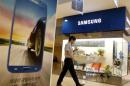 Man using his mobile phone walks past a Samsung Electronics shop in the company's main office building in central Seou