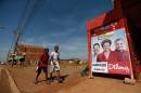 Children walk past a a campaign poster for Brazil's President Dilma Rousseff, who is running for reelection with the Workers Party (PT), ahead of general elections in the Sol Nascente neighborhood of Brasilia, Brazil, Thursday, Oct. 2, 2014. Brazil will hold general elections on Oct. 5. (AP Photo/Eraldo Peres)