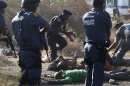 FILE - In this photo taken Thursday, Aug. 16, 2012 Police surround the bodies of striking miners after opening fire on a crowd at the Lonmin Platinum Mine near Rustenburg, South Africa. The state of South Africa's police forces came into sharp focus last week during Pistorius' bail hearing where police stumbled and fumbled in the bail hearing of Pistorius who is charged with the shooting death of his girlfriend Reeva Steenkamp. The judicial system and its ruthless police force was the backbone of the racist Apartheid system. Now, almost two decades after Mandela ended the all-white regime in 1994, this system is creaking under corruption and mismanagement. (AP Photo/File)