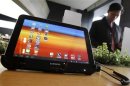 A visitor looks around behind Samsung Electronics' Galaxy Tab 10.1 tablet displayed for customers at a registration desk at KT's headquarters in Seoul