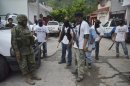 A Mexican army soldier talks to armed members of a local self-defense group wearing white T-shirts with the slogan 