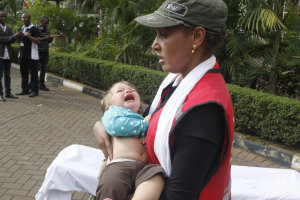 A Red Cross assistant helps a child outside the Westgate …
