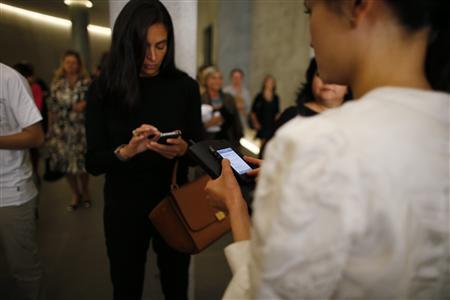 Women use their iPhones during Milan Fashion Week September 20, 2012. Picture taken September 20, 2012. REUTERS/Stefano Rellandini