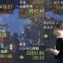 A man checks his mobile phone in front of an electronic stock board of a securities firm in Tokyo Thursday, Dec. 6, 2012 as Japan's Nikkei 225 index, top center, rose 78.60 points to 9,547.44.  Asian stock markets remained in a holding pattern Thursday as investors assessed President Barack Obama's comments that reaching a budget deal to prevent the U.S. from a possible recession was "not that tough" and could even be done quickly. (AP Photo/Koji Sasahara)