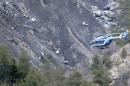 A rope hangs from a rescue helicopter flying past debris of the Germanwings passenger jet, scattered on the mountainside, near Seyne les Alpes, French Alps, Tuesday, March 24, 2015. A Germanwings passenger jet carrying at least 150 people crashed Tuesday in a snowy, remote section of the French Alps, sounding like an avalanche as it scattered pulverized debris across the mountain. (AP Photo/Claude Paris)