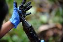 A woman shows crude oil from the Aguarico 4 well near Aguarico, Sucumbios province, Amazonian Peru, on September 17, 2013